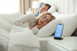 © New Africa - Couple sleeping in bed and smartphone with alarm clock app indoors, selective focus
