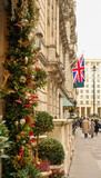 London street displaying festive Christmas decorations, Union Jack flag flying high, people walking on sidewalk