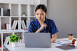 © David - Nurse, woman and studying with books at desk for medical research, information and knowledge. Home, healthcare and reading with laptop in living room for diagnosis reference, guide and treatment plan