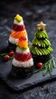 Three creatively decorated sushi cones resembling festive trees, garnished with colorful toppings, served on a dark slate plate.