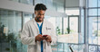 © peopleimages.com - Phone, man and doctor in hospital with typing for texting, communication or email for telehealth. Happy, technology and healthcare worker with cellphone for contact, networking or medical support.