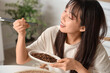 © Pixel-Shot - Young Asian woman eating fried insects in kitchen, closeup
