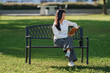 © Phimwilai - Young asian woman reading book on park bench
