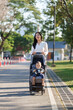 © Phimwilai - Young mother pushing a baby stroller outdoors in park