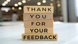© Sabbir Media - Wooden blocks stacked to spell out thank you for your feedback on a light surface in an office setting