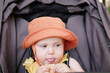© splitov27 - Little baby in hat sits in a stroller and eats cookies outdoors