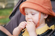 © splitov27 - Little baby in hat sits in a stroller and eats cookies outdoors