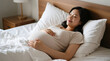 © Nata - Pregnant woman peacefully lying in bed with hands on belly in cozy bedroom