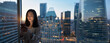 © insta_photos - Young busy Asian business woman executive using mobile cell phone technology at night in dark office. Professional businesswoman holding digital smartphone with evening city view from window. Banner
