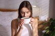 © New Africa - Beautiful woman with cup of aromatic coffee at home