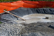 © knelson20 - New residential housing development construction site, concrete washout and containment area with black tarp below and orange safety fencing, sunny fall day