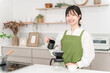 © buritora - Young Asian woman in an apron making coffee in the kitchen