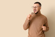© Pixel-Shot - Young man eating cookie on beige background