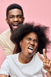 © SHOTPRIME STUDIO - Happy African American couple having fun on a pink background, showing playful emotions with vibrant colors and casual clothing