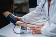 © Tj - Doctor checking female patient blood pressure during health checkup