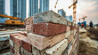 © Yurij - Pile of old weathered bricks stacked on a construction site with cranes and unfinished buildings blurred in the background during sunset hours
