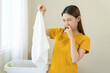 © KMPZZZ - Bad smell nose, bad asian young housewife woman having smelling clothes her towel, sniff smelly dirty stinky musty, look disgusting from clothes after washed, laundry out of washing machine at home.