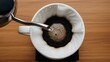 © SITI - Barista Hands Pouring Hot Water into Filter for Fresh Drip Coffee Brewing Process on Wooden Table