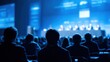 © Shuvo - Audience engaging in a professional conference with a panel of speakers on a brightly lit blue stage