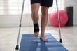 © New Africa - Man with hurt leg using crutches indoors, closeup