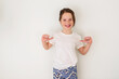 © RooM The Agency - Portrait of a smiling girl standing in front of a white wall pointing her thumbs at herself