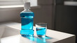 © Muhammad - A bottle of blue mouthwash and a glass on a white bathroom countertop