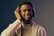 © SHOTPRIME STUDIO - Young African man enjoying music with headphones, dressed in stylish attire, smiling against a colorful gradient background that evokes joy and relaxation