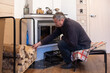 © lara-sh - Senior man loading firewood into home fireplace indoors