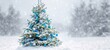 © Gurav - The Christmas tree decorated with blue baubles stands in a snowy winter field