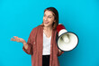 © luismolinero - Young caucasian woman isolated on blue background holding a megaphone and with surprise facial expression