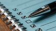 © STK - A close up shot focuses on a metallic ballpoint pen marking a checkbox on a light blue notepad. The notepad is spiral bound and rests on a wooden surface.
