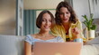 © stockbusters - Two girls watching website in living room closeup. Smiling friends discussing
