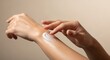 © The Little Hut - Woman applying moisturizing cream on her arm for skincare routine, beauty concept against beige background