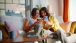 © stockbusters - Laughing besties holding cellphones sitting cozy home couch. Smiling girlfriends