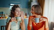 © stockbusters - Two sisters gossiping kitchen holding coffee cups closeup. Happy women friends