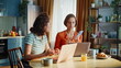 © stockbusters - Sad friends closing laptop after bad phone call sitting kitchen. Upset two women