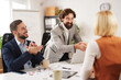 © Stockphotodirectors - Group of professionals gathers around a table in a meeting room during the day to discuss strategies, brainstorm ideas, and strengthen their teamwork for achieving goals together.