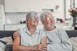 © Daniel - Happy senior couple relaxing together at home on sofa, elderly retired woman and partner looking out the window while sharing a calm moment, enjoying peaceful domestic life and emotional connection