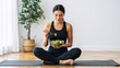© Vasiliy - Fit woman in sportswear eating a healthy salad after a workout. Young female sitting on a yoga mat at home. Healthy lifestyle and nutrition concept