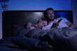 © ronstik - married couple in the bed at home bedroom, husband watching TV late night while wife sleeping
