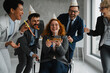 © Novak - A group of cheerful diverse colleagues surprising a businesswoman with a birthday cake in a modern open-space office. The scene shows a joyful atmosphere, teamwork, and workplace friendship