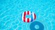 © ahmta - Red White and Blue Striped Inflatable Swim Ring Floating in Crystal Clear Blue Swimming Pool Water
