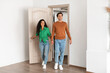 © Prostock-studio - A cheerful couple holds hands as they walk through the doorway of their new apartment. Their expressions show happiness and excitement as they explore their stylish living space.