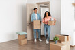© Prostock-studio - A young couple stands inside their new house, holding cardboard boxes. They appear frustrated and confused as they navigate their first home together, unsure of their decision.