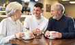 © JackF - Family participants relatives sitting in cafe, talking, drinking coffee and having nice conversation. Senior couple and guy sitting at table, talking, laughing, joking, chatting