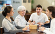 © JackF - Young man and women sit at a table in a coffee shop and actively communicate with the older generation, they discuss family plans. Elderly people met with grandchildren