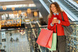 © Jelena - Woman enjoying shopping experience holding coffee in mall