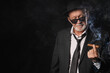 © Pixel-Shot - Old businessman smoking cigar on black background