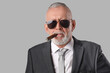 © Pixel-Shot - Old businessman in sunglasses smoking cigar on grey background