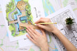 © Pixel-Shot - Woman drawing zoning plan on city map, top view